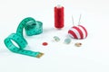 Set of sewing accessories: A green measuring centimetric tape l , the scattered buttons, the coil of red threads on a white Royalty Free Stock Photo