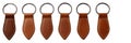 Set of six leather zipper pulls in various brown tones attached to key rings white background Royalty Free Stock Photo
