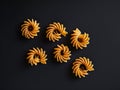 A set of six pastas on a black surface