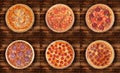 A set of six pizzas on a wooden background. 1 With tuna 2 With jalapeno 3 Devil 4 Salami 5-6 Pepperoni