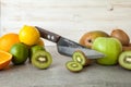 Fresh citrus fruits, half cut kiwi orange and lemons on cutting board with knife on stone background. Royalty Free Stock Photo