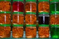 A set of small jars of different colors with jam without labels.