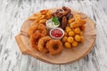 A set of snacks for beer. BBQ wings, croquettes, cheese sticks, onion rings and chips. With tomato and cheese sauce. On a round Royalty Free Stock Photo