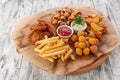 A set of snacks for beer. Nuggets, French fries, dumplings, onion rings and chips. With tomato and cheese sauce. On a round wooden Royalty Free Stock Photo