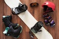 Set of snowboard boots, helmet, gloves and mask on wooden