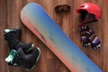 Set of snowboard boots, helmet, gloves and mask on wooden