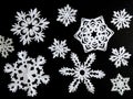 Set of snowflakes cut out of white paper on a black background. Handmade new year and Christmas decoration Royalty Free Stock Photo
