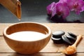 A set for spa procedures, hot massage stones, bath salts and flavored water collected from a bamboo stem into a bowl, orchid flowe Royalty Free Stock Photo