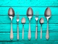 A set of spoons and forks on a turquoise wooden background. Royalty Free Stock Photo