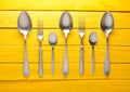 A set of spoons and forks on a yellow wooden table. Royalty Free Stock Photo