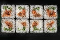 Set of square maki rolls with fried salmon, curd cheese and green bamboo leaf in a black ceramic plate with chopstick on a dark Royalty Free Stock Photo