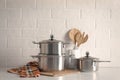 Set of stainless steel cookware and kitchen utensils on table near white wall Royalty Free Stock Photo