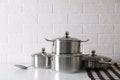 Set of stainless steel cookware on table near white brick wall Royalty Free Stock Photo