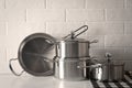 Set of stainless steel cookware on table near white brick wall Royalty Free Stock Photo