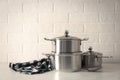 Set of stainless steel cookware on table near white brick wall Royalty Free Stock Photo