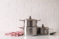 Set of stainless steel cookware on table near white brick wall Royalty Free Stock Photo