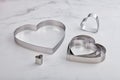 Set of stainless steel heart-shaped cookie cutters on a white marble surface Royalty Free Stock Photo