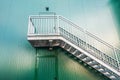 Set of stairs and a door in the green painted wall into the side of an industrial building Royalty Free Stock Photo