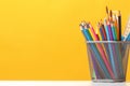 A set of stationery on the table. Pencils, brushes, paints on the background of the yellow wall. The concept of education, study.