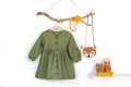 Set of stylish child clothes. Hanger with green dress, brown bag, accessories for hair on wooden stick, shoes on shelf. Fashion