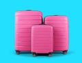 Set of stylish plastic pink suitcases for travel on blue background.