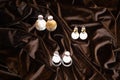 A set of stylish trendy earrings on crumpled brown fabric background. Fashionable women's costume jewelry for a party