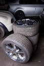 A set of stylish tuned wheels with shiny chrome disks folded into the composition against the background of cars in the workshop