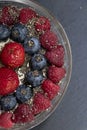 Set of summer berries with oatmeal and chia seeds in a small glass bowl on a black stone background. Perfectly healthy summer