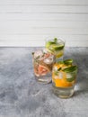 Set summer cold drinks with different citrus in glasses on a gray background. Cocktail with grapefruit, orange, lemon lime and ice Royalty Free Stock Photo