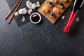 Set of sushi and maki rolls with branch of white flowers and bottle of champagne on stone table