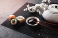 Set of sushi and maki rolls with branch of white flowers and teapot with the inscription green tea on stone table Royalty Free Stock Photo