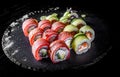 Set of sushi roll with tuna, avocado, cream cheese, cucumber, rice in plate on black wooden table Royalty Free Stock Photo