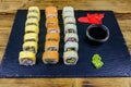 Set of sushi rolls on a black stone slate on wooden table Royalty Free Stock Photo