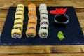 Set of sushi rolls on a black stone slate on wooden table Royalty Free Stock Photo