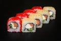 Set of sushi rolls with masago and sesame caviar stuffed with salmon and cheese on a black background.