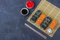 Set of sushi rolls with salmon and with omelet, tofu and vegetables, flying fish roe, tempura on makisu on a dark background. Royalty Free Stock Photo