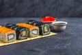 Set of sushi rolls with salmon and with omelet, tofu and vegetables, flying fish roe, tempura on makisu on a dark background. Royalty Free Stock Photo