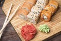 Set of sushi rolls with salmon, sesame, red caviar, ginger and wasabi, sticks for sushi on a light wooden board Royalty Free Stock Photo