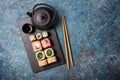 Set of sushi rolls served on a black slate board with chopsticks and asian teapot Royalty Free Stock Photo