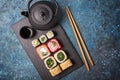 Set of sushi rolls served on a black slate board with chopsticks and asian teapot Royalty Free Stock Photo