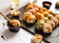 Set of sushi rolls with shrimp, salmon, avocado on a stone plate, one roll dipped in soy sauce Royalty Free Stock Photo