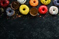 Set of sweet colored donuts with a cup of coffee on a black stone table. Royalty Free Stock Photo