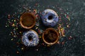Set of sweet colored donuts with a cup of coffee on a black stone table. Royalty Free Stock Photo