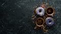 Set of sweet colored donuts with a cup of coffee on a black stone table. Royalty Free Stock Photo