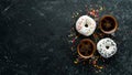 Set of sweet colored donuts with a cup of coffee on a black stone table. Royalty Free Stock Photo