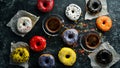 Set of sweet colored donuts with a cup of coffee on a black stone table. Royalty Free Stock Photo