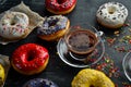 Set of sweet colored donuts with a cup of coffee on a black stone table. Royalty Free Stock Photo