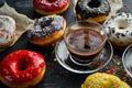 Set of sweet colored donuts with a cup of coffee on a black stone table. Royalty Free Stock Photo