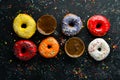 Set of sweet colored donuts with a cup of coffee on a black stone table. Royalty Free Stock Photo