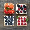 Set of sweet sandwiches with cream-cheese and fresh forest berries over a wooden background Royalty Free Stock Photo